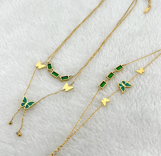 A set of two golden chains with green butterfly and rectangular bead accents.  A golden cuff bracelet with Roman numerals and small crystals.